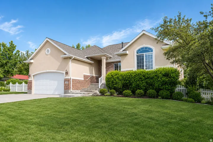 Stucco and brick exterior with a prominent arched window and a two-car garage