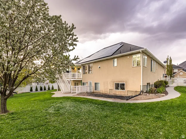 Back of house with a patio, solar panels, stucco siding, and a wooden deck