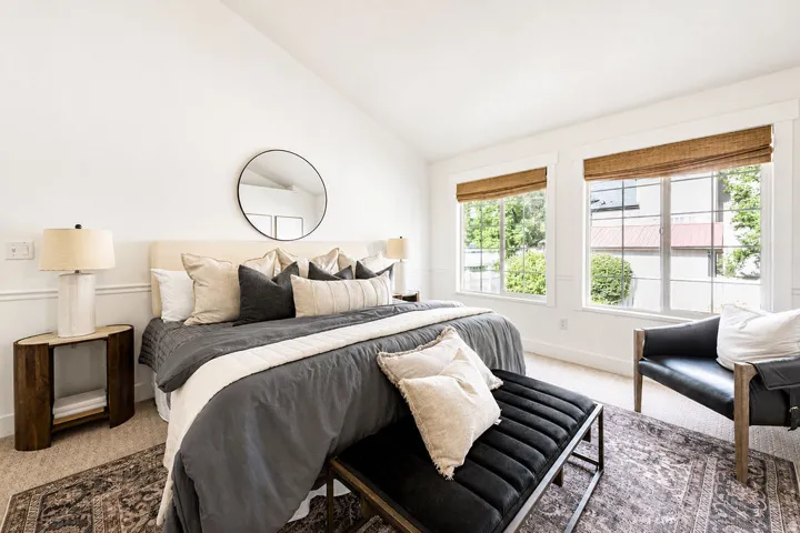 Spacious bedroom with vaulted ceilings, multiple windows, wainscoting, and carpet flooring