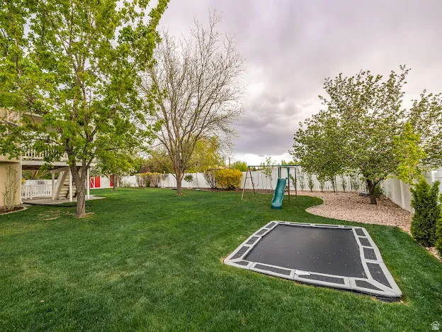 Fenced backyard with a trampoline and a playground