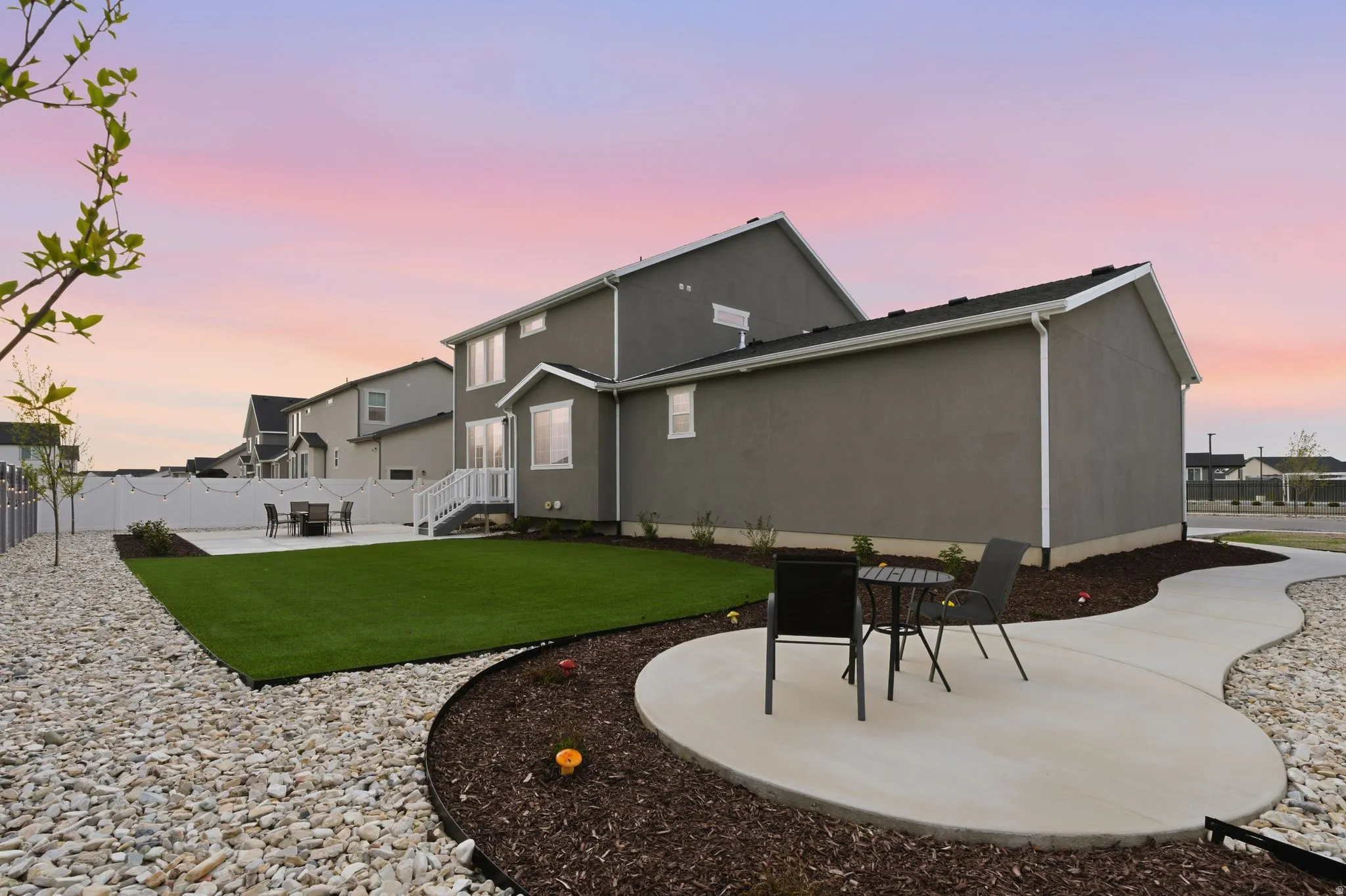 Back of house at dusk featuring a patio area, stucco siding, and a fenced backyard