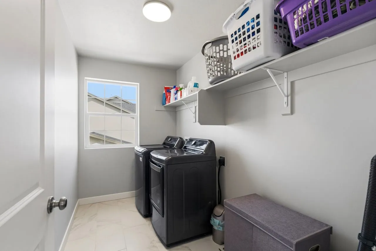Laundry room featuring light marble finish flooring and washer and clothes dryer
