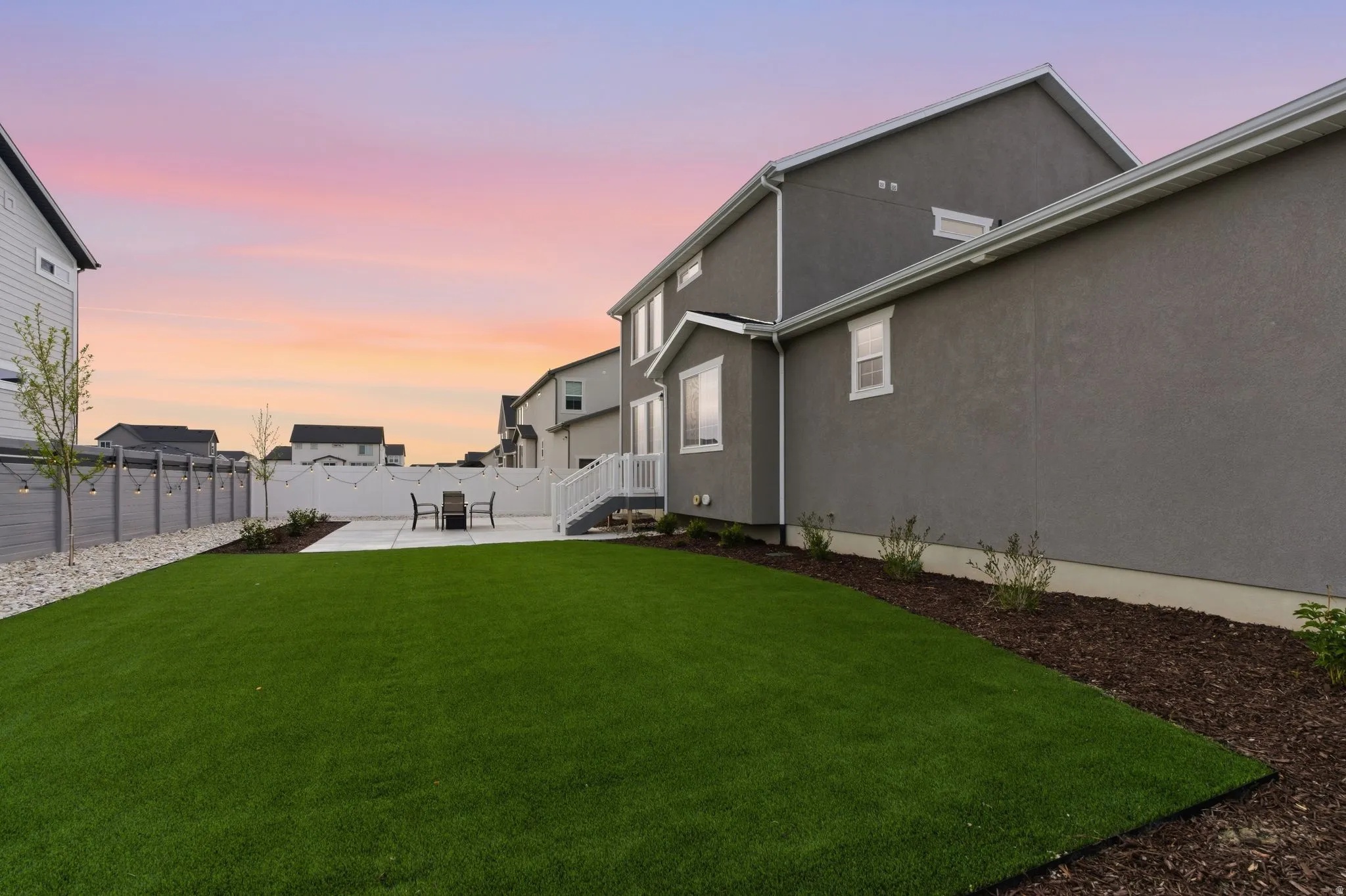 Yard at dusk with a fenced backyard and a patio