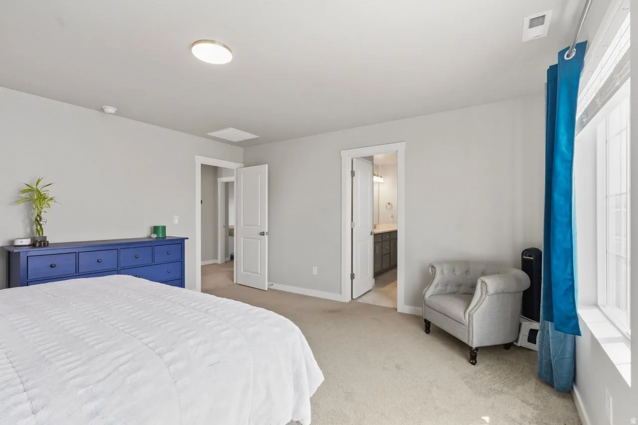 Bedroom featuring light colored carpet and ensuite bath