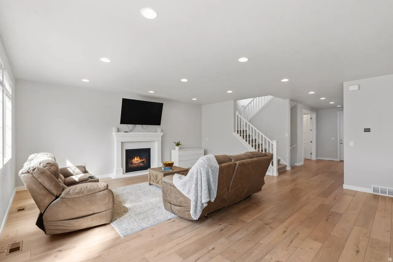 Living room with a glass covered fireplace, light wood-type flooring, and recessed lighting
