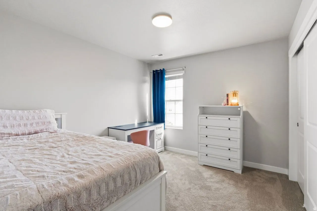 Bedroom with light carpet and a closet