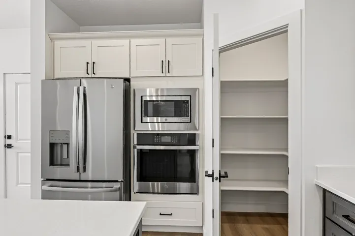Kitchen area featuring white shaker cabinetry, stainless steel French door refrigerator, built-in microwave, and built-in oven