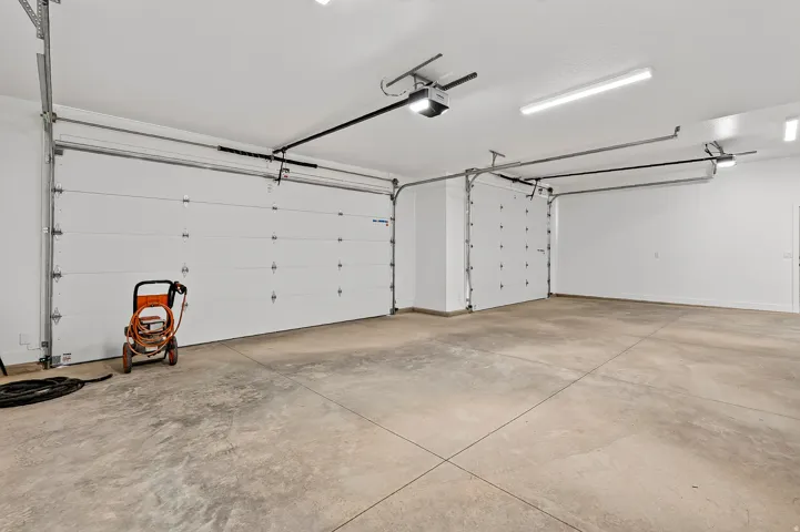 Spacious garage featuring two overhead doors with automatic openers, a concrete floor, and bright overhead lighting