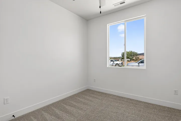 Neutral wall paint, plush carpet flooring, white trim, and a window with white framing