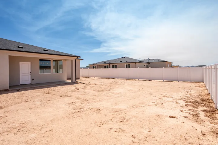 Rear exterior featuring a covered patio with concrete flooring, a white door, and multiple windows