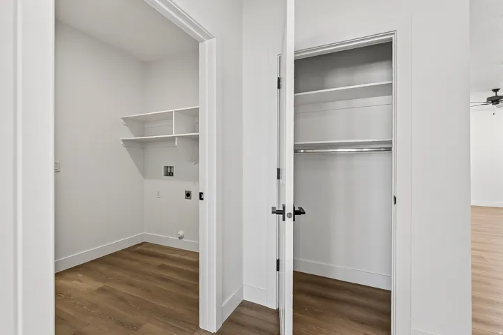 Dedicated laundry room with wood-finish flooring, white walls, and built-in shelving