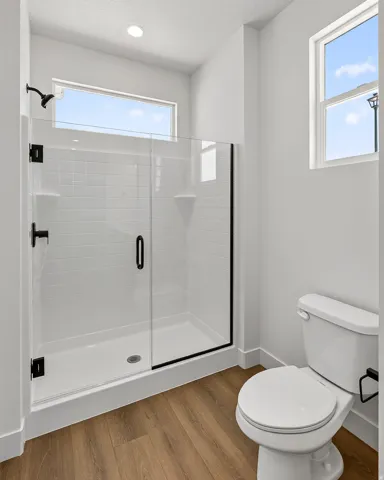 Full bathroom featuring a walk-in shower with clear glass enclosure and matte black hardware, white subway tile surround, and built-in shelving