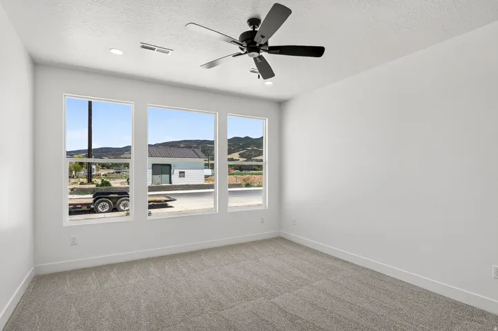 Interior space featuring three large windows, a ceiling fan with integrated lighting, recessed lighting, and light-colored carpeting