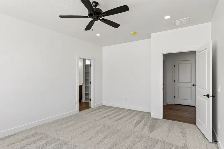 Spacious room featuring light-toned carpet, a black ceiling fan, recessed lighting, and white baseboards