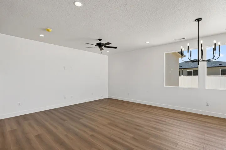 Spacious room featuring wood-finish flooring, recessed lighting, and a contemporary black chandelier
