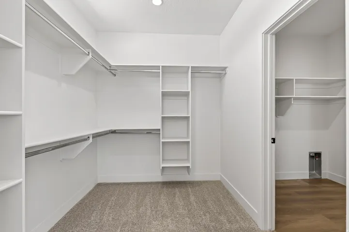 Walk-in closet featuring extensive built-in shelving and hanging rods