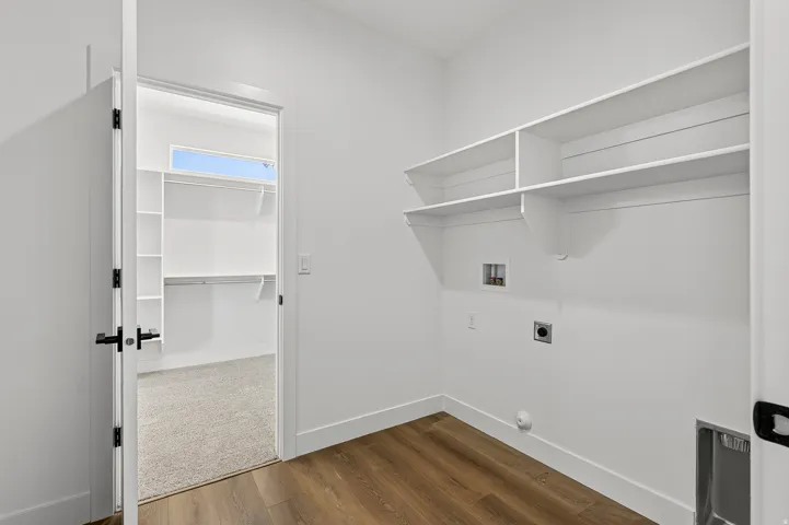 Laundry area featuring wood-finish flooring, built-in shelving, and connections for appliances