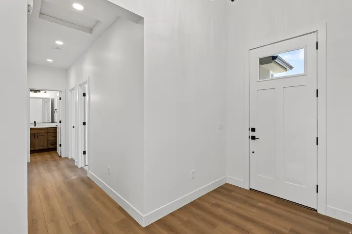 Entryway featuring a white paneled door with an upper window, wood-finish flooring, white baseboards, and recessed lighting