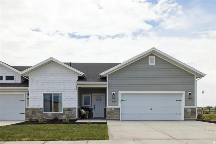 Contemporary exterior featuring light gray siding, white shake accents, and stone veneer detailing