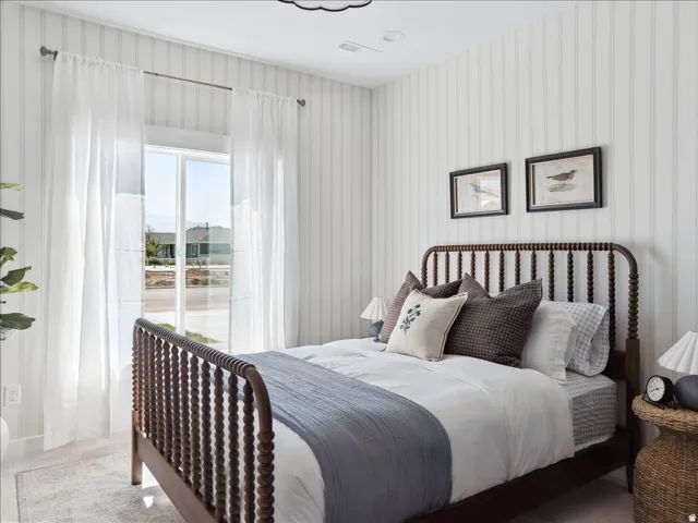 Bedroom featuring vertical striped wallpaper, white baseboards, and a large window with sheer white curtains