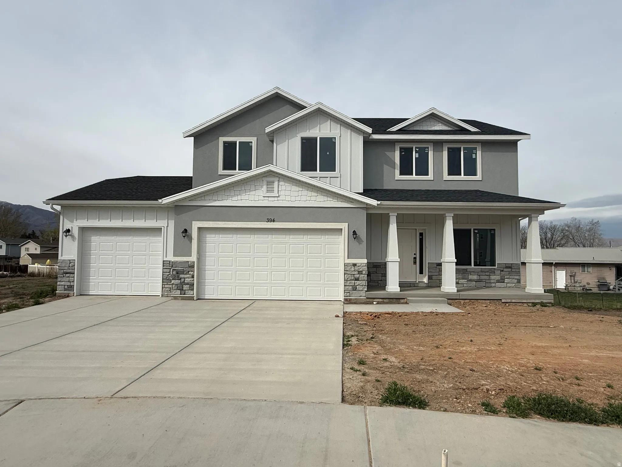Craftsman-style house featuring covered porch, stone siding, driveway, an attached garage, and board and batten siding
