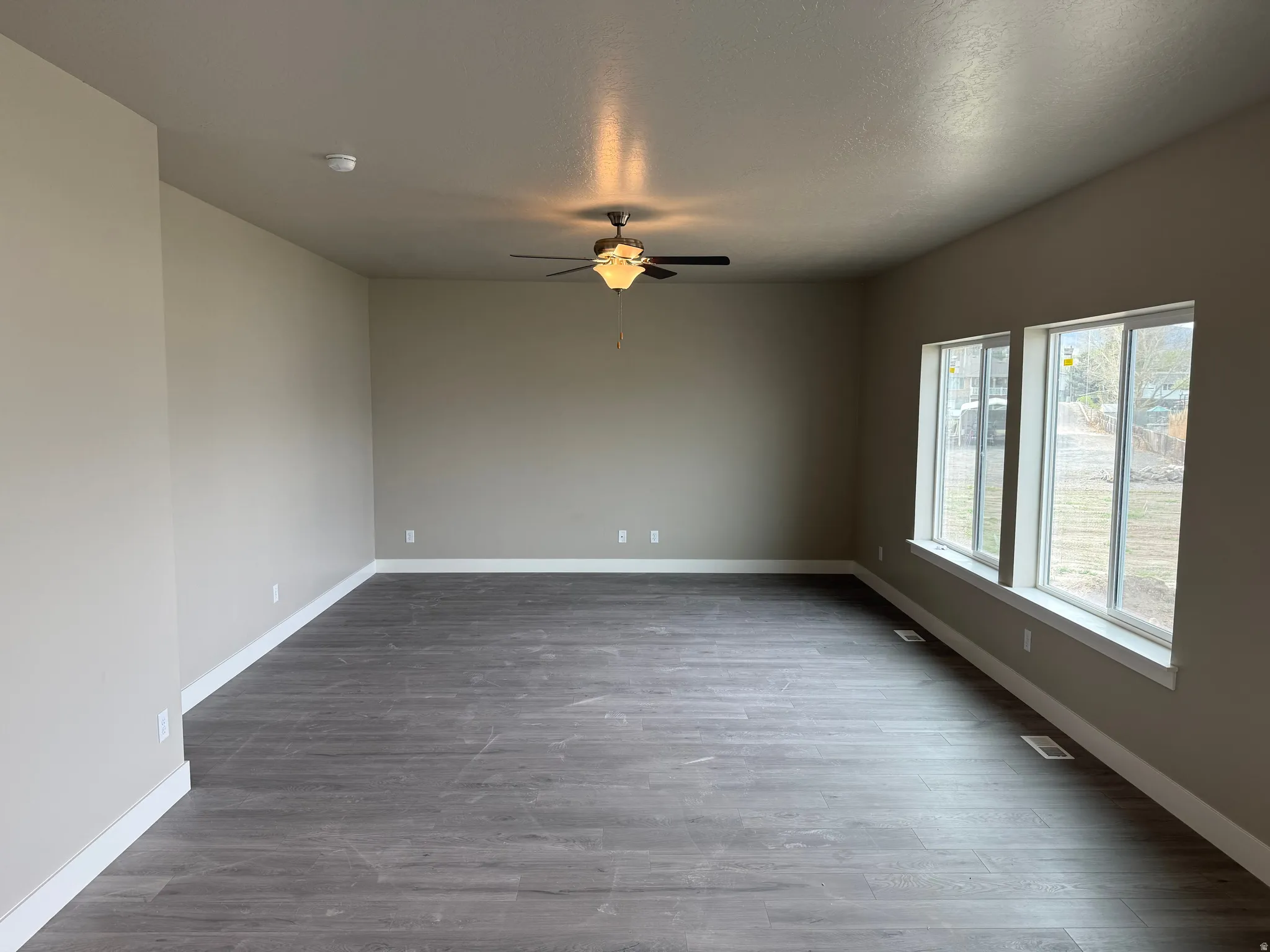 Spare room featuring dark wood finished floors and a ceiling fan