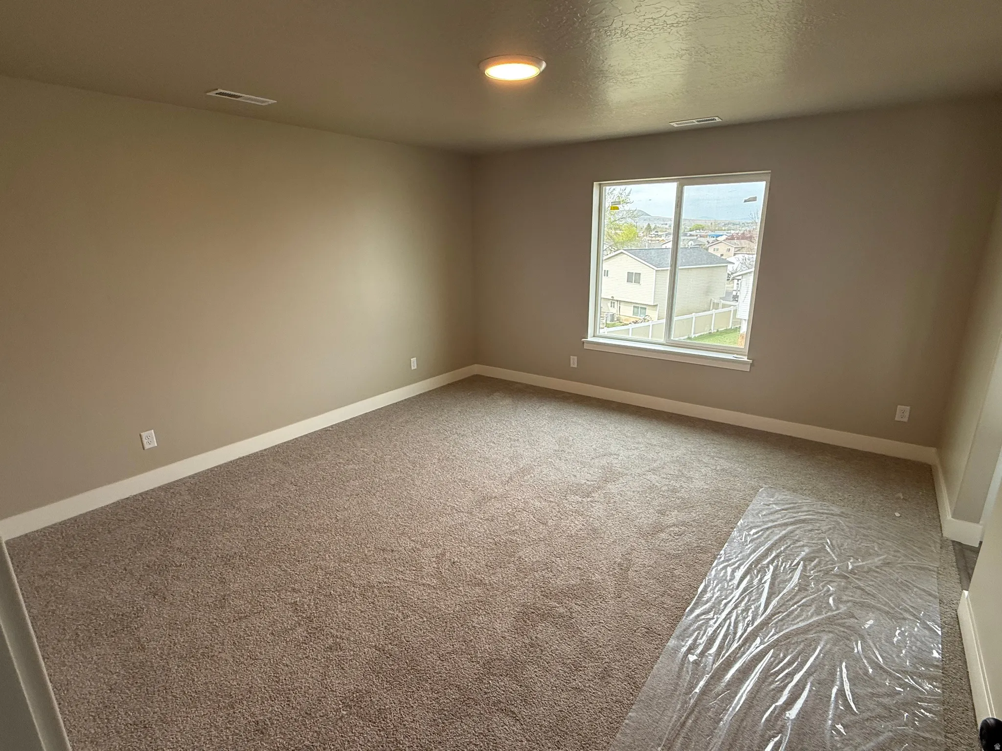 Unfurnished room featuring light carpet and a textured ceiling