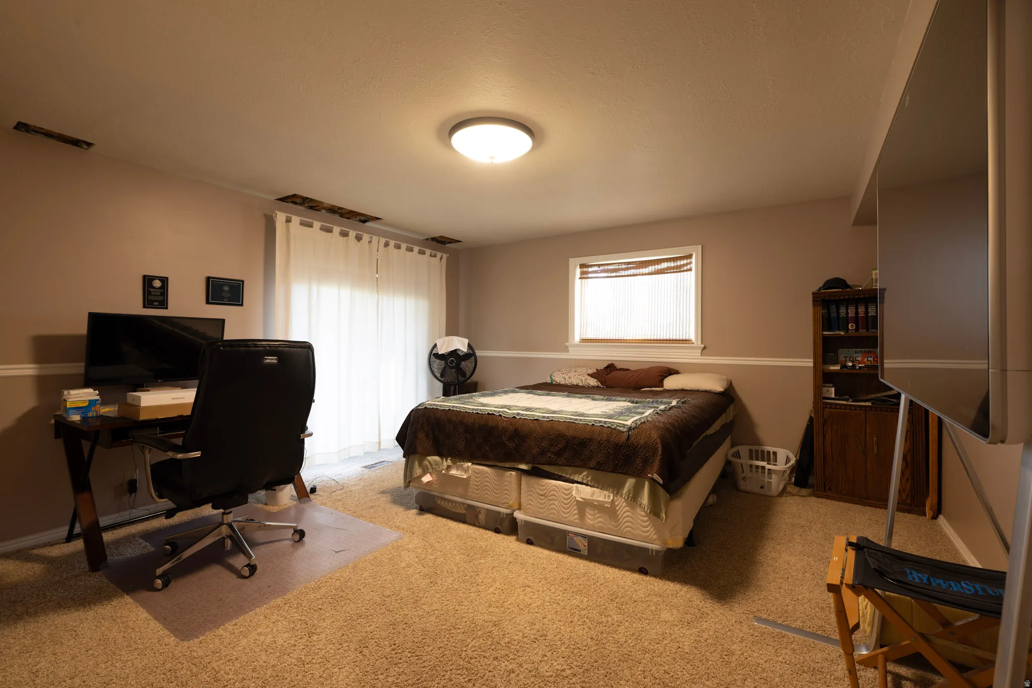 Bedroom featuring light carpet, multiple windows, and a desk