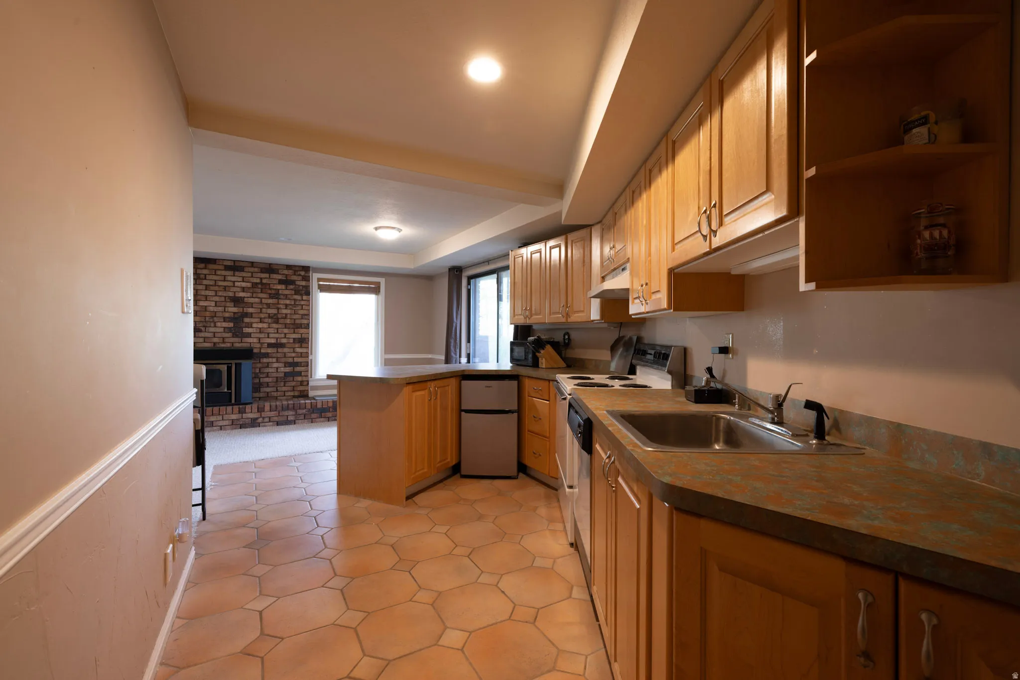 Kitchen with stainless steel refrigerator, a peninsula, open shelves, white range with electric cooktop, and light wood finish cabinets
