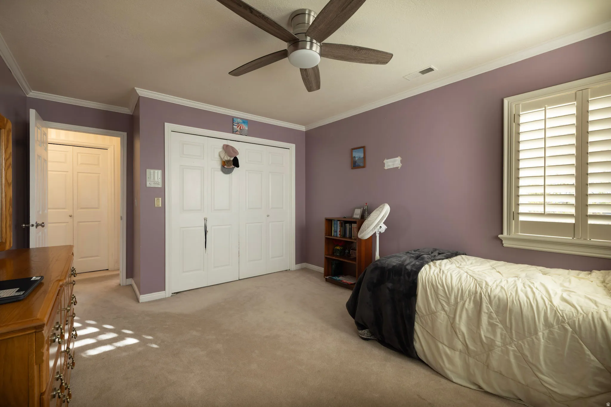 Bedroom with crown molding, a closet, light carpet, and ceiling fan