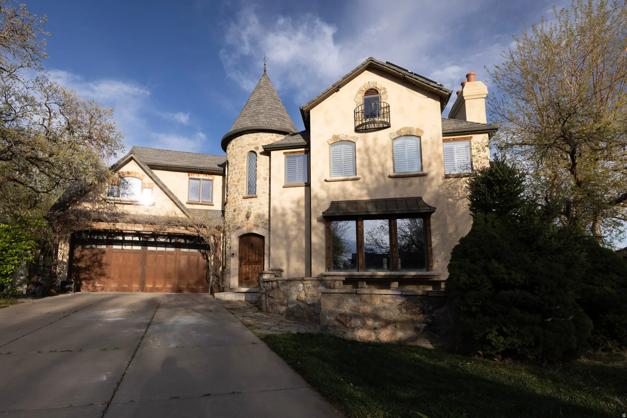French provincial home featuring a chimney, stucco siding, driveway, stone siding, and a garage