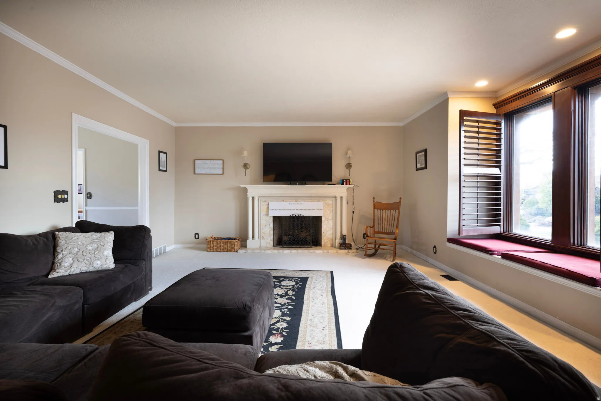 Carpeted living room with a fireplace and ornamental molding