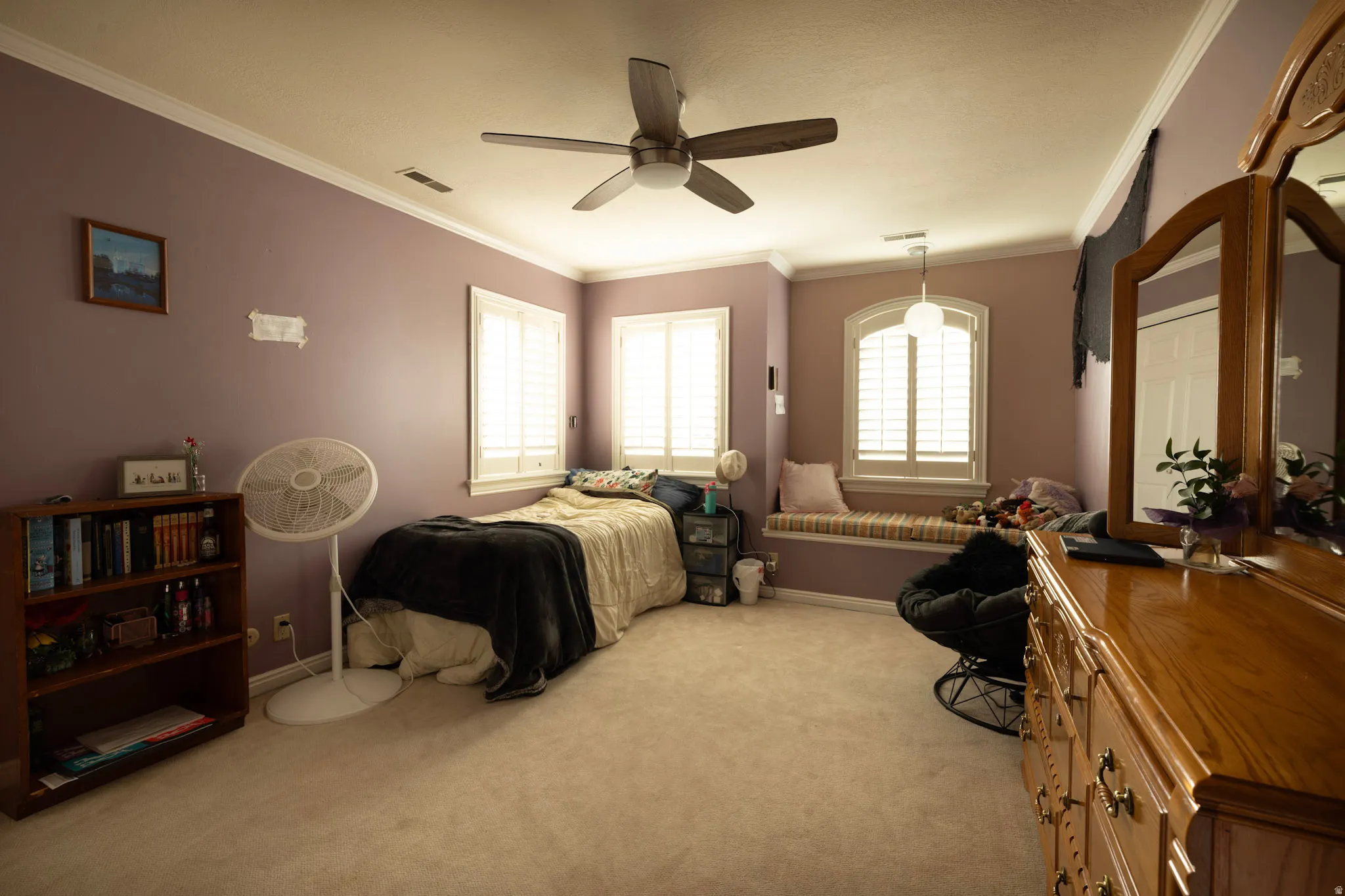 Bedroom with crown molding, light colored carpet, and a ceiling fan