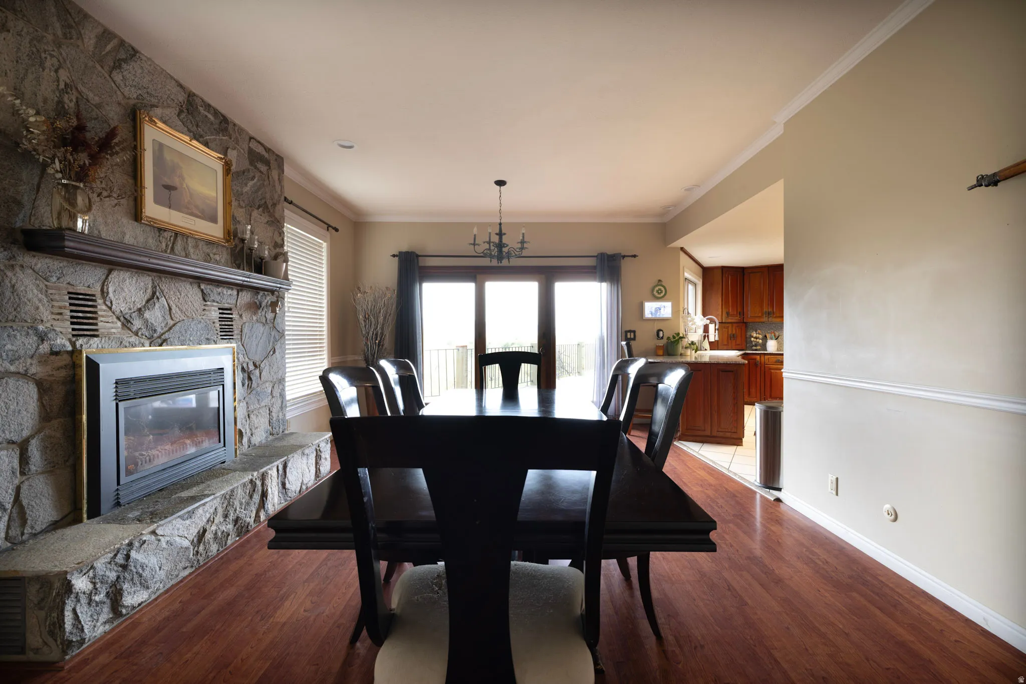 Dining area with crown molding, dark wood finished floors, a fireplace, and a chandelier