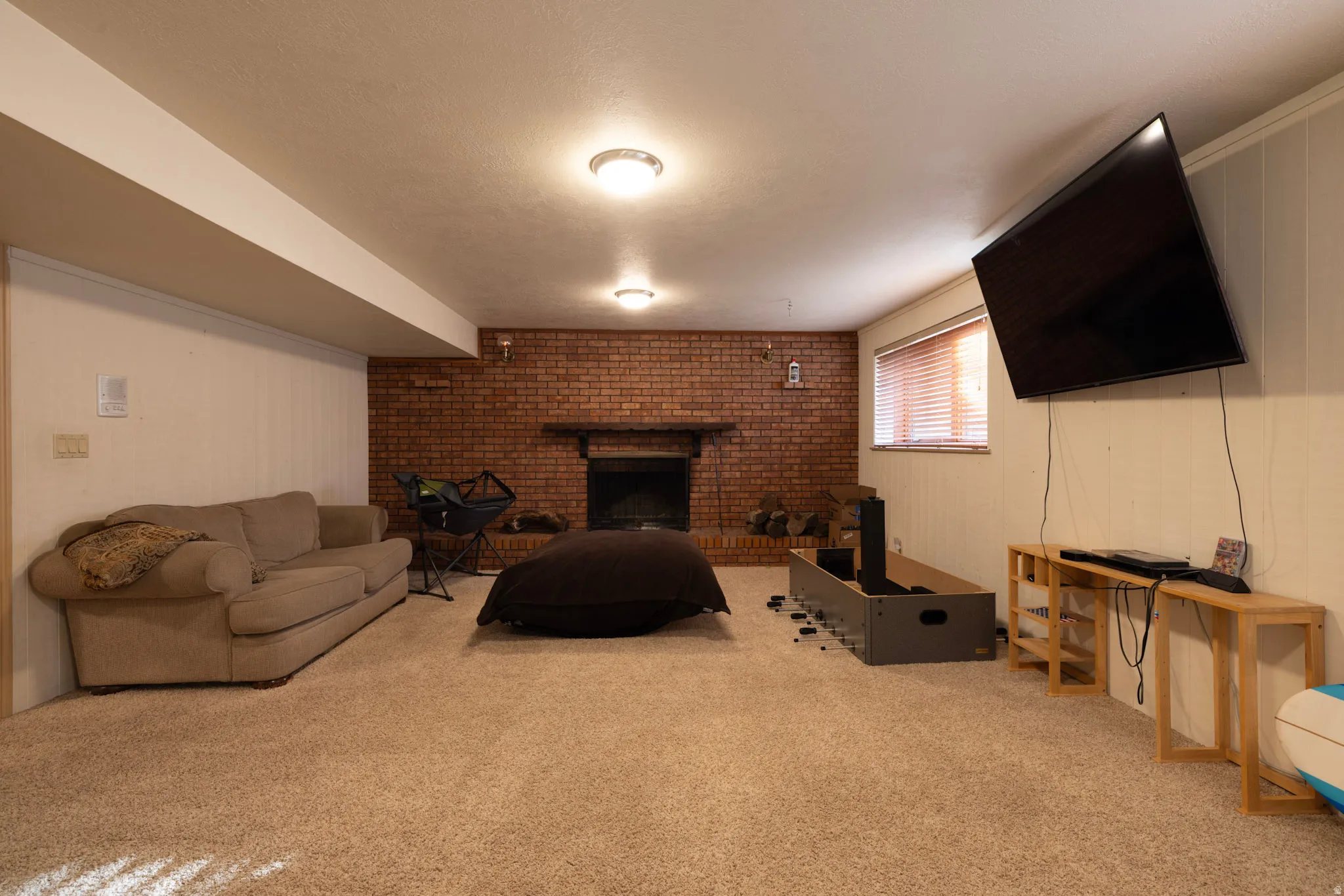Carpeted living room featuring a fireplace and brick wall