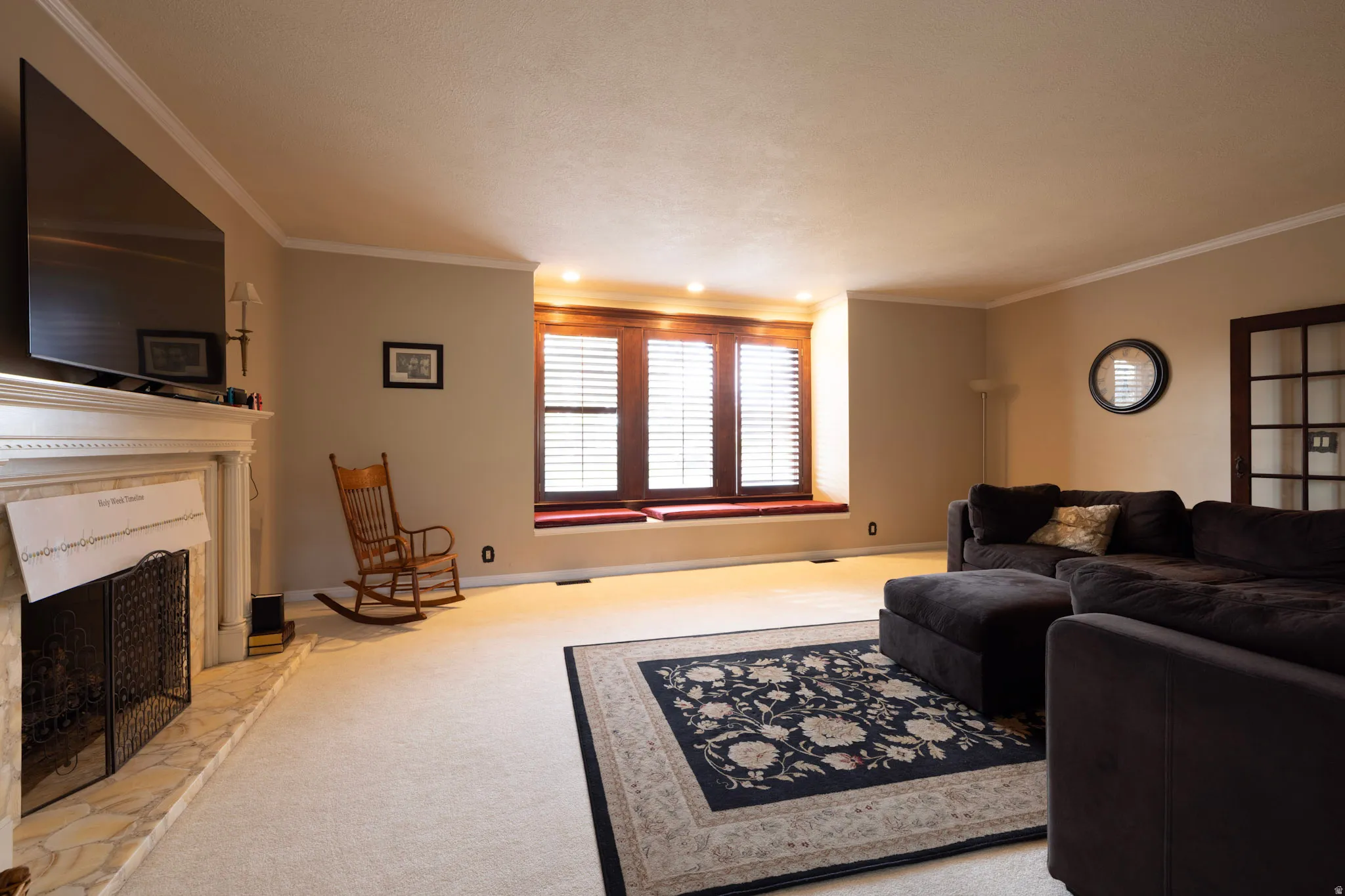 Living room featuring a high end fireplace, light colored carpet, and crown molding