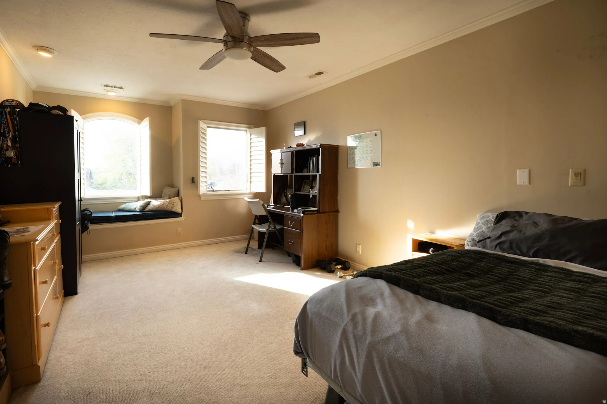 Bedroom featuring crown molding, ceiling fan, light colored carpet, and a desk