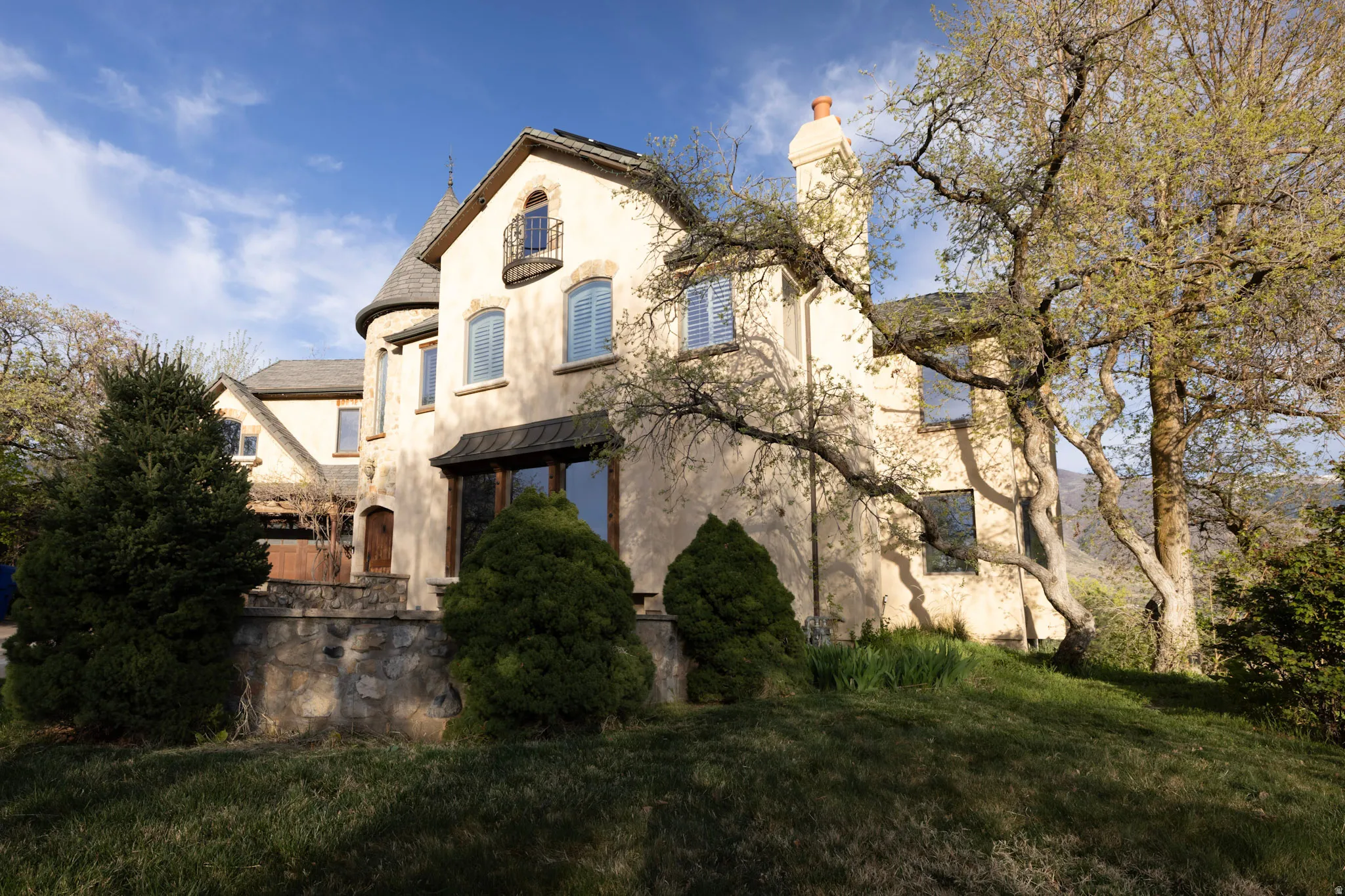 View of front facade featuring a standing seam roof, stucco siding, a chimney, and a front yard
