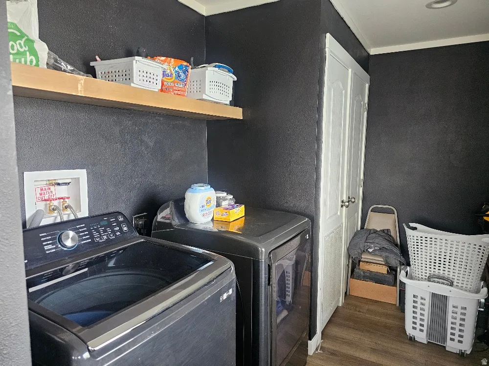 Laundry area featuring dark wood-type flooring, washer and clothes dryer, and ornamental molding