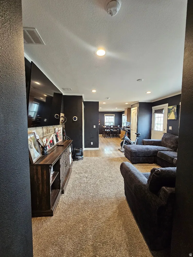 Living room with a textured ceiling, light carpet, and recessed lighting