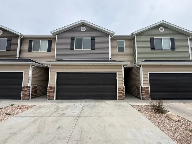 View of front facade with stone siding, driveway, and an attached garage