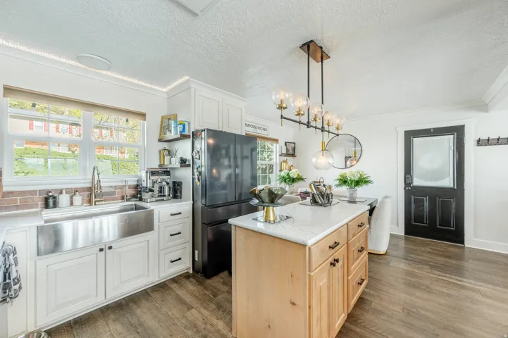 Dual tone kitchen with freestanding refrigerator, dual tone cabinets, dark wood finished floors, crown molding, and a kitchen island