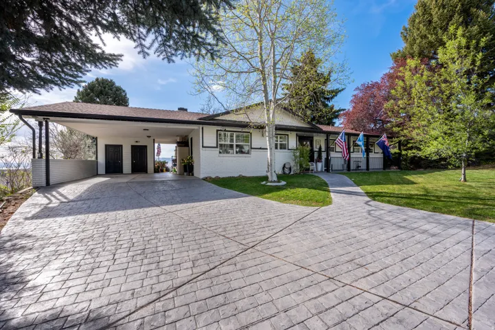Ranch-style house with driveway, brick siding, a front yard, and an attached carport