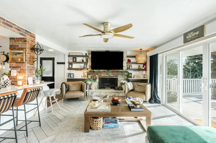 Living area featuring a fireplace, ceiling fan, and a textured ceiling