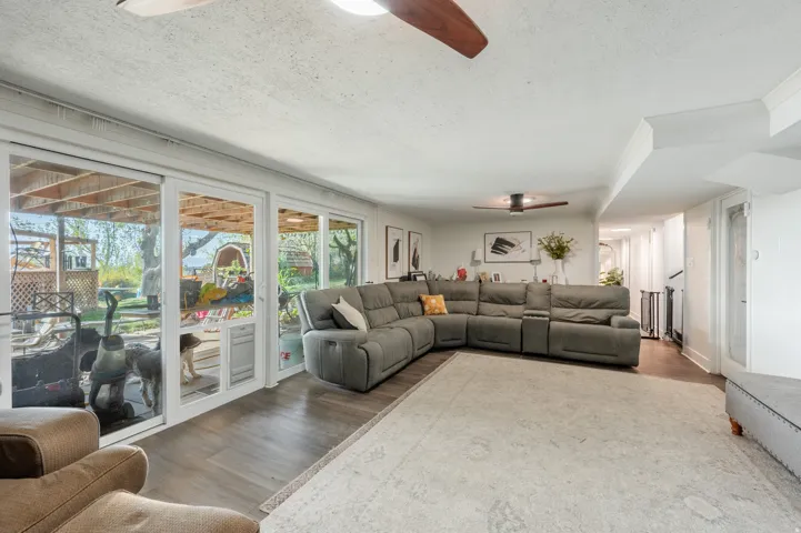 Living area with ceiling fan, a textured ceiling, and wood finished floors