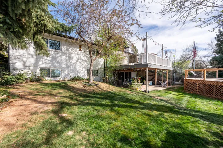 Rear view of property featuring a patio, a lawn, a deck, and brick siding