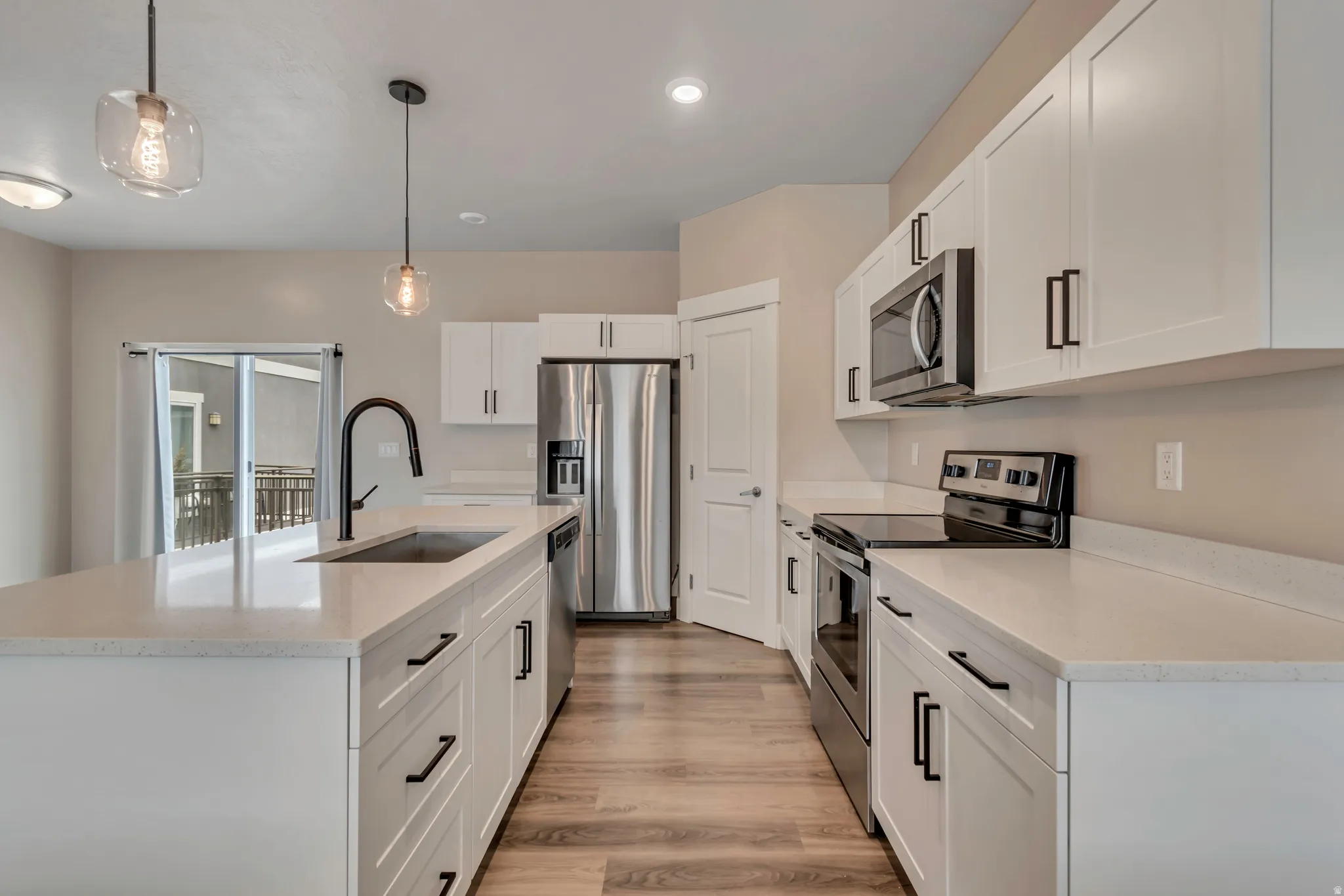 Kitchen with white cabinets, stainless steel appliances, and pantry.