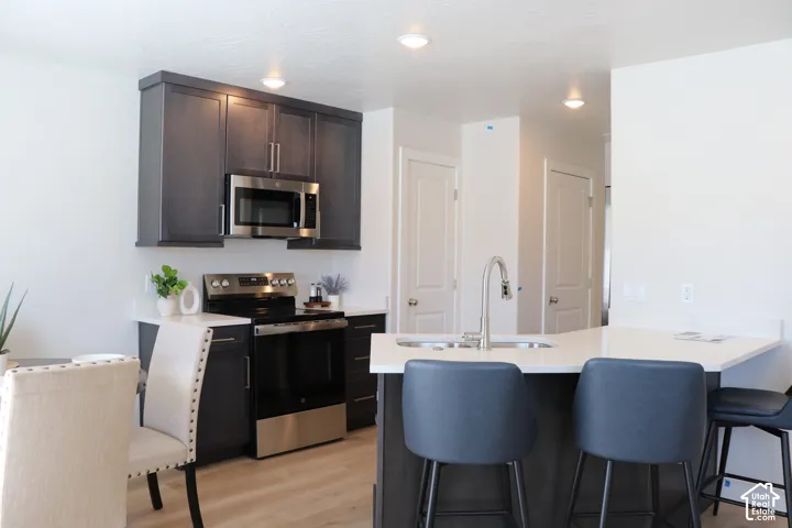 Modern kitchen featuring dark wood-finish cabinetry with stainless steel hardware, stainless steel microwave, and stainless steel electric range