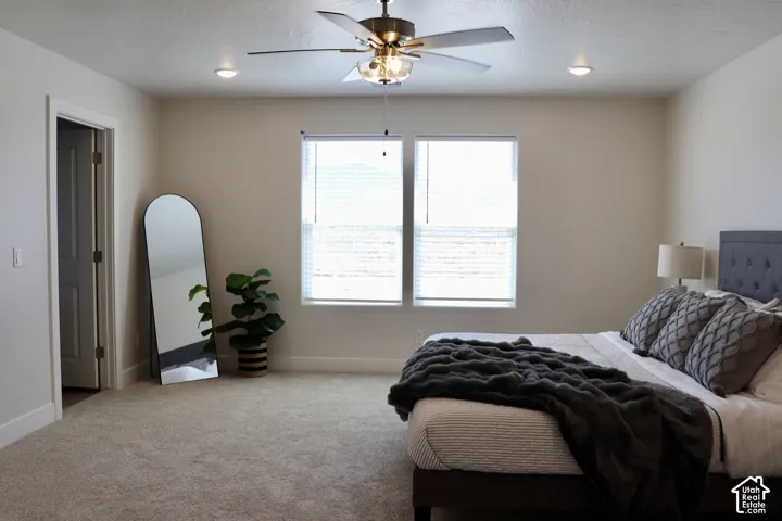 Spacious bedroom featuring light-colored walls, neutral carpet, and two windows with blinds