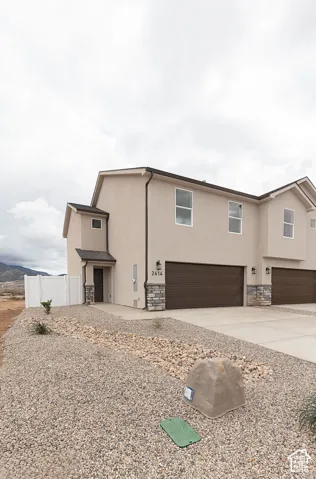View of front of house featuring a garage, stucco siding, stone siding, and concrete driveway